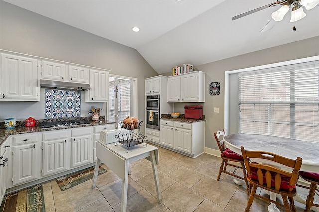 kitchen featuring light tile patterned floors, white cabinets, lofted ceiling, appliances with stainless steel finishes, and under cabinet range hood