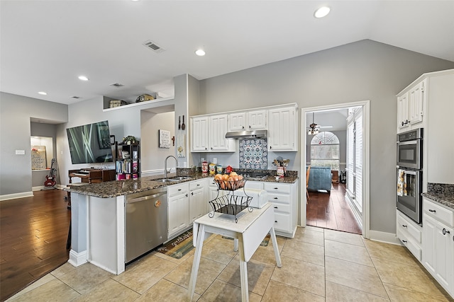 kitchen with a peninsula, appliances with stainless steel finishes, white cabinets, and a sink