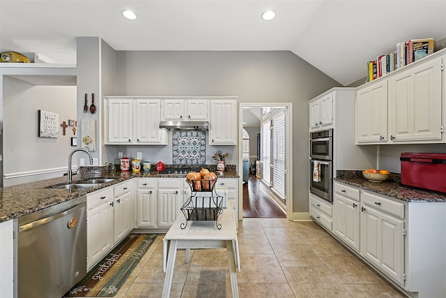 kitchen featuring dark stone counters, stainless steel appliances, a sink, and white cabinetry