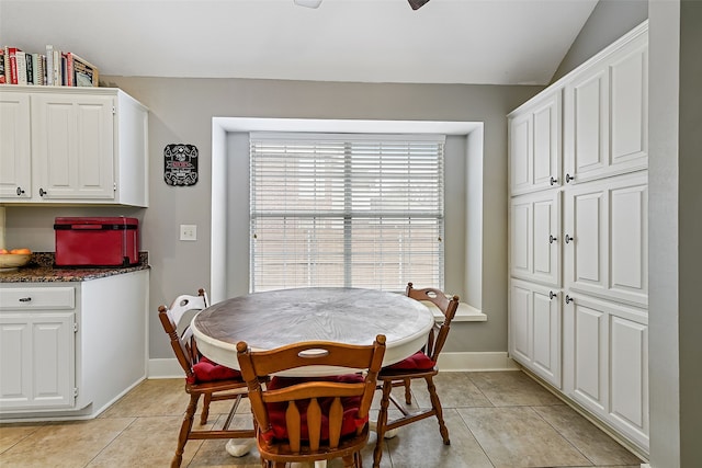 dining room with light tile patterned floors, lofted ceiling, and baseboards