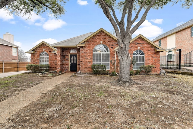 ranch-style house featuring fence and brick siding