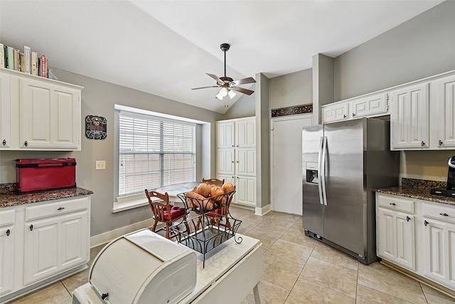 kitchen with white cabinets, ceiling fan, light tile patterned flooring, dark stone countertops, and stainless steel fridge with ice dispenser