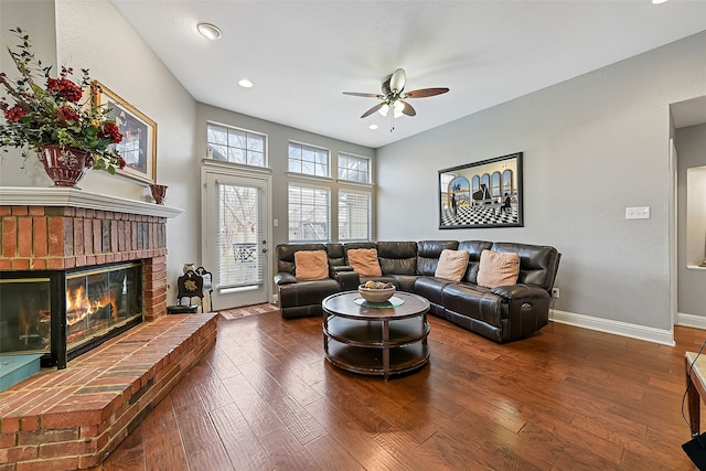 living room featuring ceiling fan, a brick fireplace, wood finished floors, and baseboards