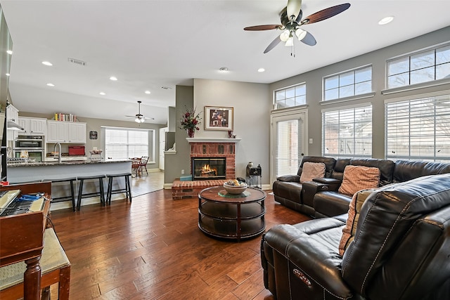 living area featuring plenty of natural light, visible vents, dark wood finished floors, and a fireplace