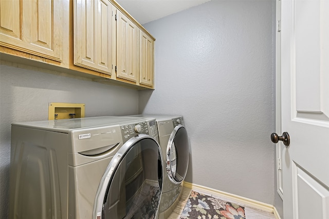 clothes washing area with baseboards, cabinet space, a textured wall, and washing machine and clothes dryer