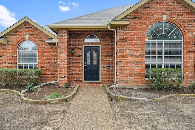 property entrance with brick siding and roof with shingles