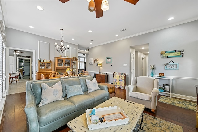 living area featuring ceiling fan with notable chandelier, visible vents, wood finished floors, and ornamental molding