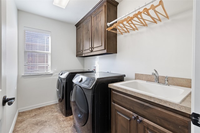 washroom with cabinet space, baseboards, washer and clothes dryer, and a sink