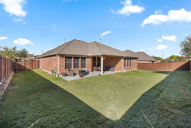 rear view of property featuring brick siding, a lawn, a patio area, and a fenced backyard