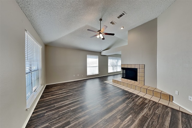 unfurnished living room with dark wood-style floors, lofted ceiling, visible vents, and a fireplace