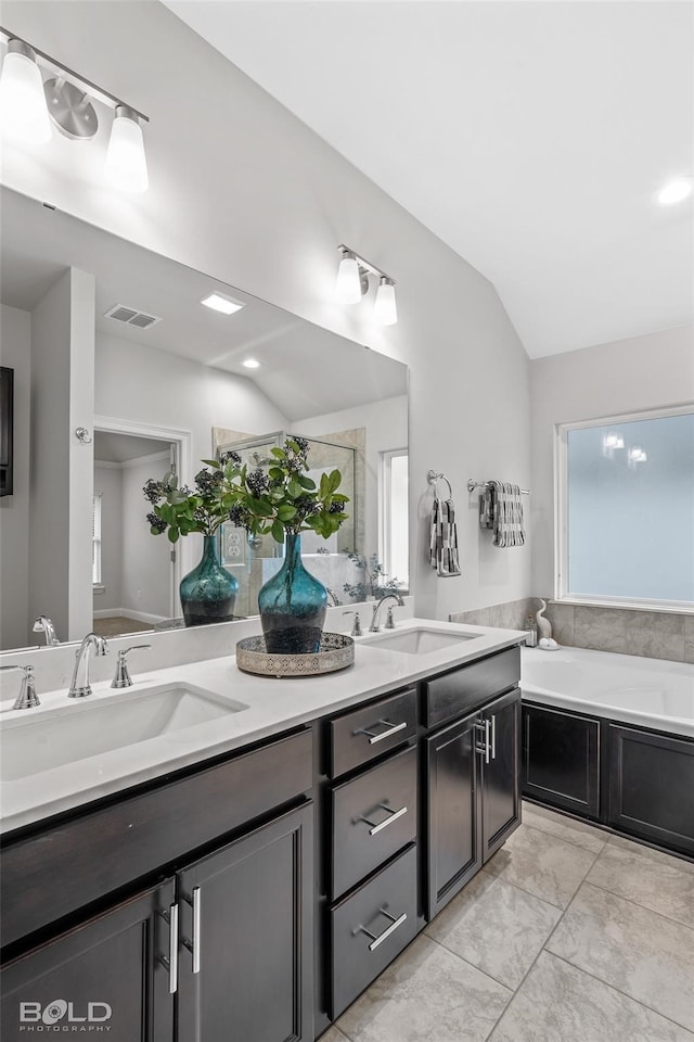 full bathroom with double vanity, visible vents, vaulted ceiling, and a sink