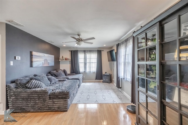 living room featuring a ceiling fan, wood finished floors, visible vents, and baseboards