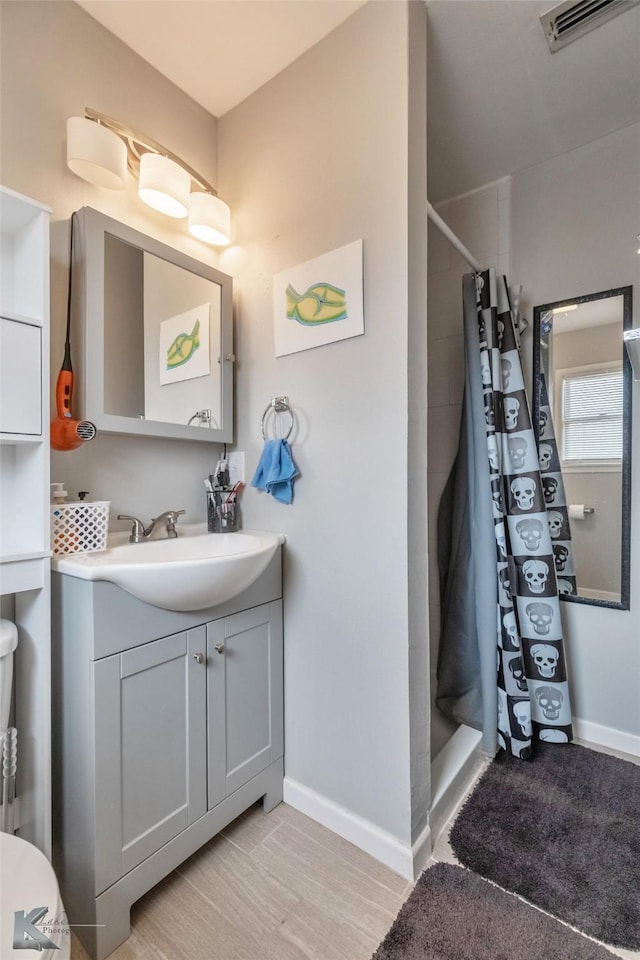 full bathroom featuring toilet, a shower with shower curtain, vanity, visible vents, and baseboards