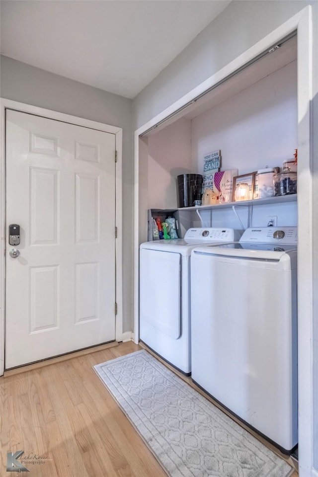 clothes washing area with laundry area, separate washer and dryer, and light wood-style flooring