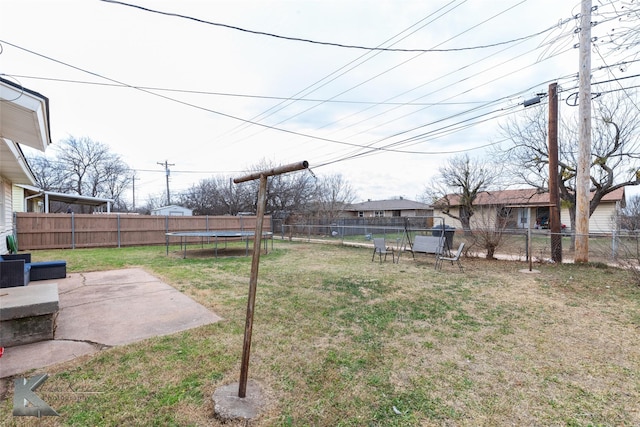 view of yard featuring a trampoline, a fenced backyard, and a patio