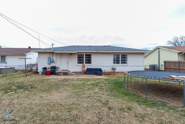 back of property featuring entry steps, central AC, fence, a yard, and a trampoline