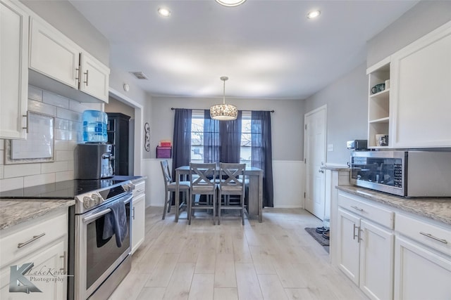 kitchen with white cabinets, wainscoting, light wood-style flooring, appliances with stainless steel finishes, and open shelves