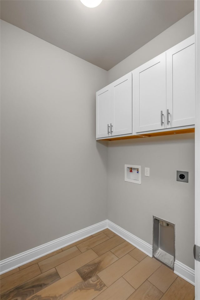 clothes washing area with hookup for a washing machine, hookup for an electric dryer, baseboards, light wood-type flooring, and cabinet space