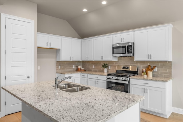 kitchen with white cabinets, decorative backsplash, vaulted ceiling, stainless steel appliances, and a sink