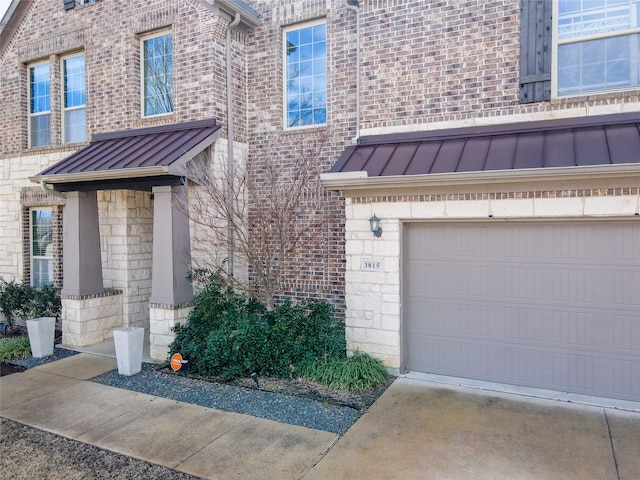 view of front of house featuring a standing seam roof, stone siding, metal roof, and concrete driveway