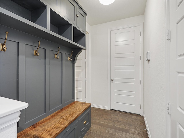 mudroom with dark wood-style floors and baseboards