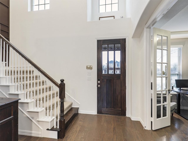 entrance foyer with dark wood finished floors, a towering ceiling, baseboards, and stairs