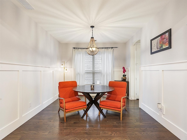 dining space with arched walkways, dark wood-style flooring, visible vents, and a decorative wall