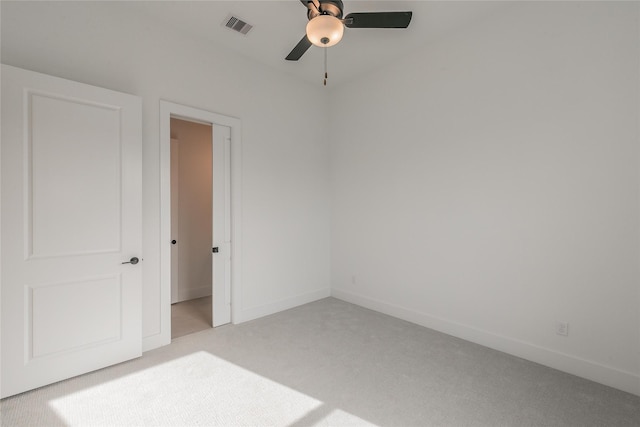 spare room featuring ceiling fan, visible vents, baseboards, and light colored carpet