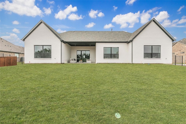 rear view of house with a patio, a shingled roof, a lawn, and fence