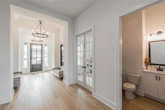 entrance foyer featuring a notable chandelier, light wood-style flooring, and baseboards