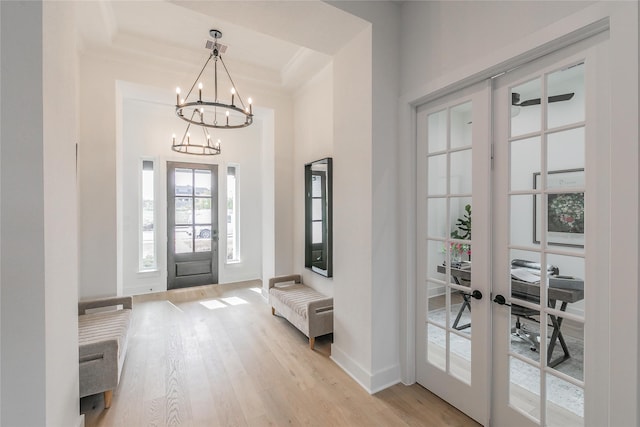 foyer entrance with light wood-style floors, baseboards, and french doors