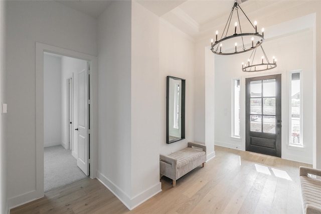 foyer entrance featuring baseboards, light wood finished floors, and an inviting chandelier