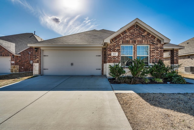 ranch-style home with a garage, driveway, central AC unit, and brick siding