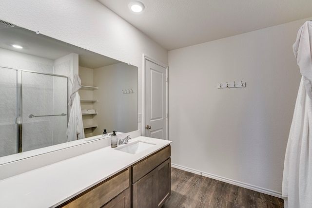 full bath with a shower stall, baseboards, wood finished floors, and vanity