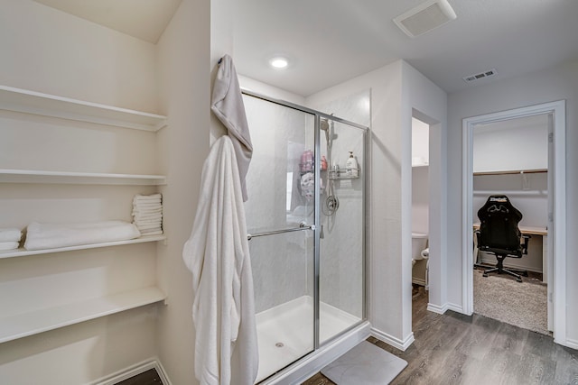 bathroom featuring a stall shower, visible vents, a spacious closet, and wood finished floors