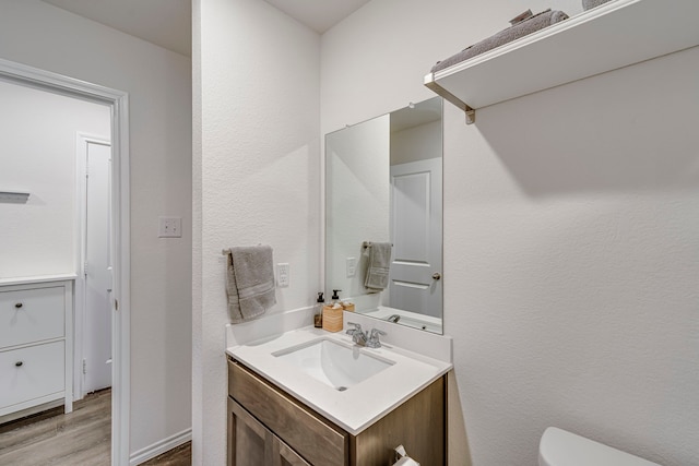 bathroom featuring toilet, wood finished floors, and vanity