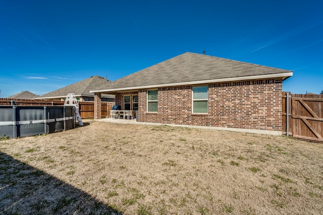 rear view of property featuring a patio area, fence, a pool, and brick siding