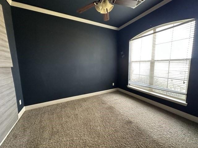 carpeted empty room with crown molding, baseboards, and ceiling fan