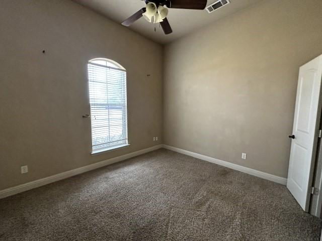 carpeted empty room with baseboards, visible vents, and ceiling fan