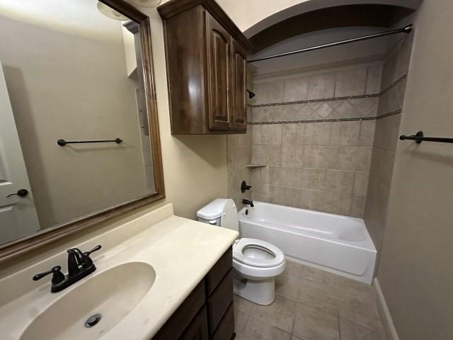 bathroom featuring baseboards, toilet, tile patterned flooring, vanity, and shower / washtub combination