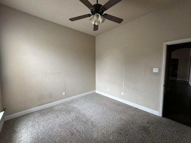 empty room with carpet floors, a ceiling fan, and baseboards