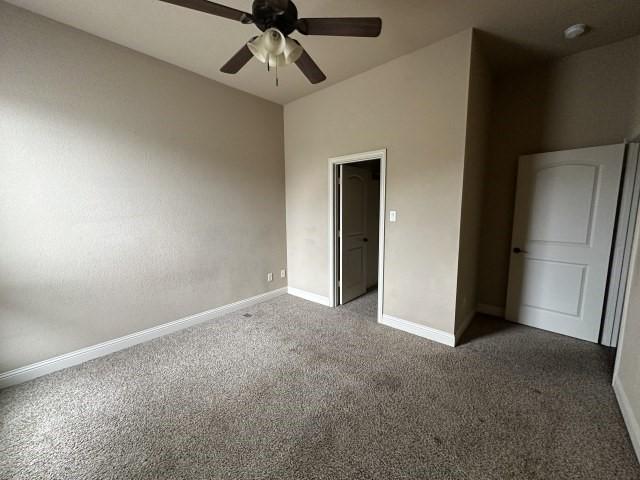 unfurnished bedroom featuring ceiling fan, dark colored carpet, and baseboards