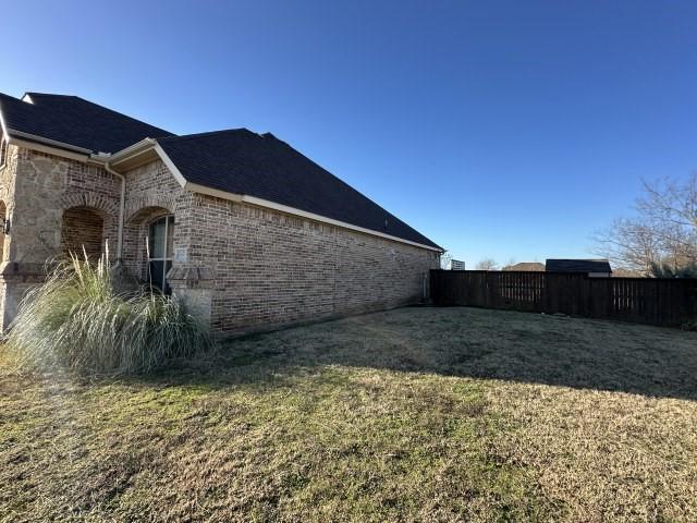 view of home's exterior featuring brick siding and a lawn