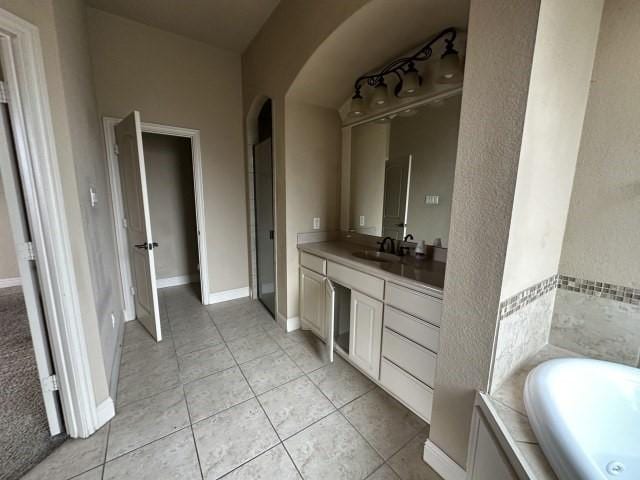 full bath featuring baseboards, vanity, a bath, and tile patterned floors