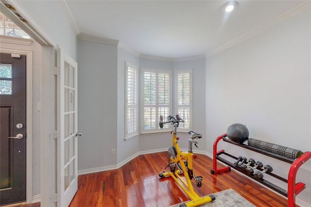 exercise room with ornamental molding, baseboards, and wood finished floors