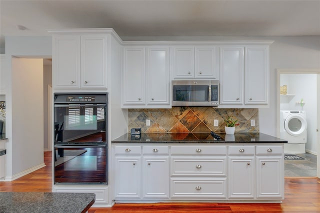 kitchen featuring light wood finished floors, black appliances, washer / clothes dryer, and white cabinets