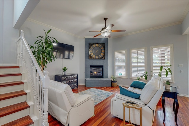 living room featuring baseboards, wood finished floors, stairs, crown molding, and a fireplace