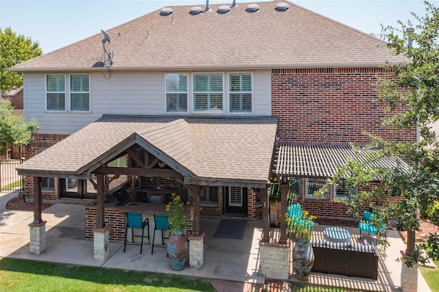 back of property featuring a patio area, a shingled roof, and an outdoor bar