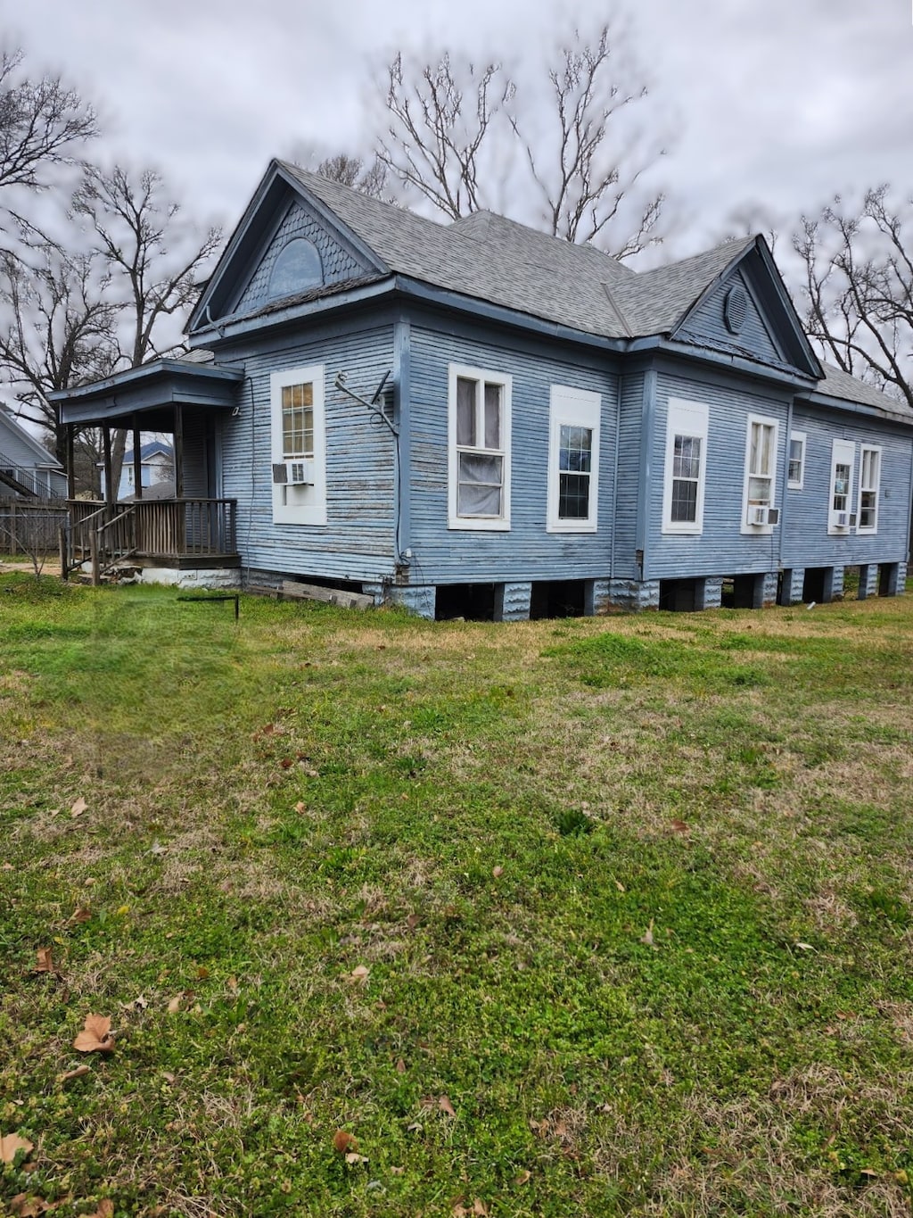 view of side of property with a lawn, cooling unit, and roof with shingles