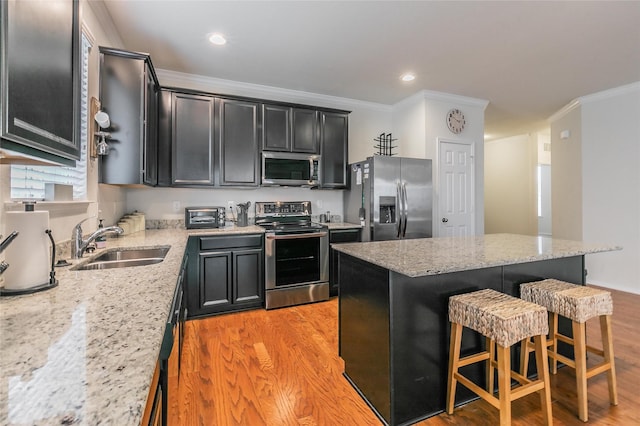 537 Running Water Trl, Fort Worth, TX 76131 - kitchen featuring appliances with stainless steel finishes, light wood finished floors, a kitchen bar, crown molding, and dark cabinetry